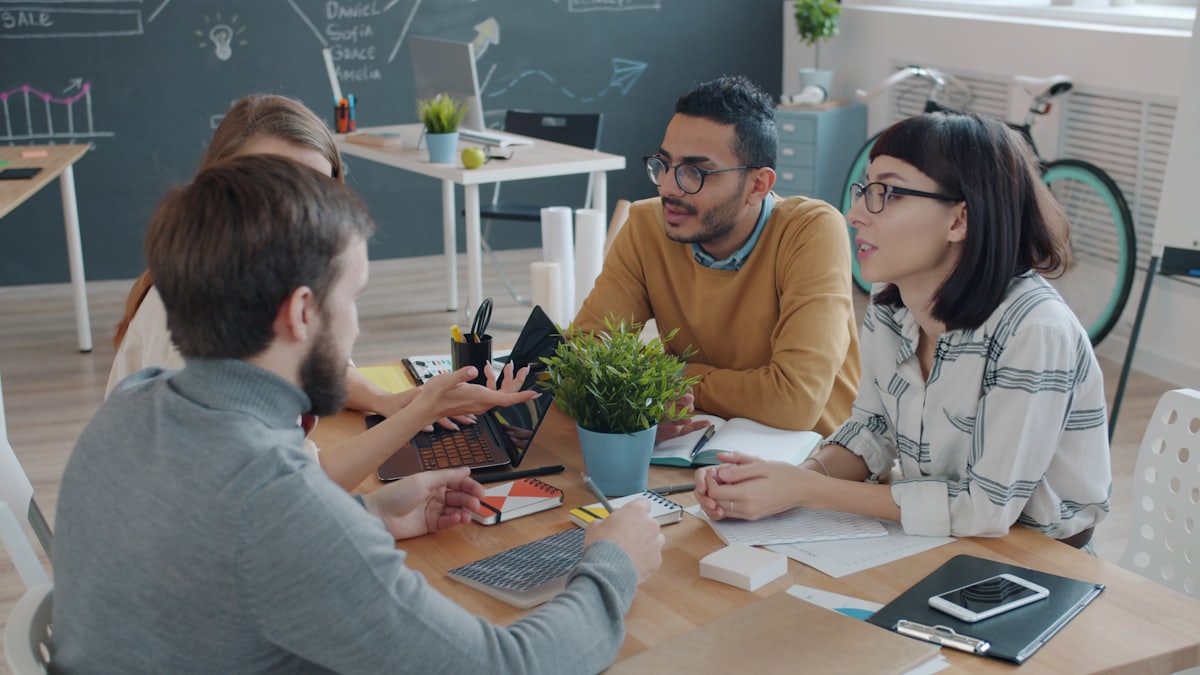 Coworkers of different backgrounds collaborating around a table during a staff meeting.